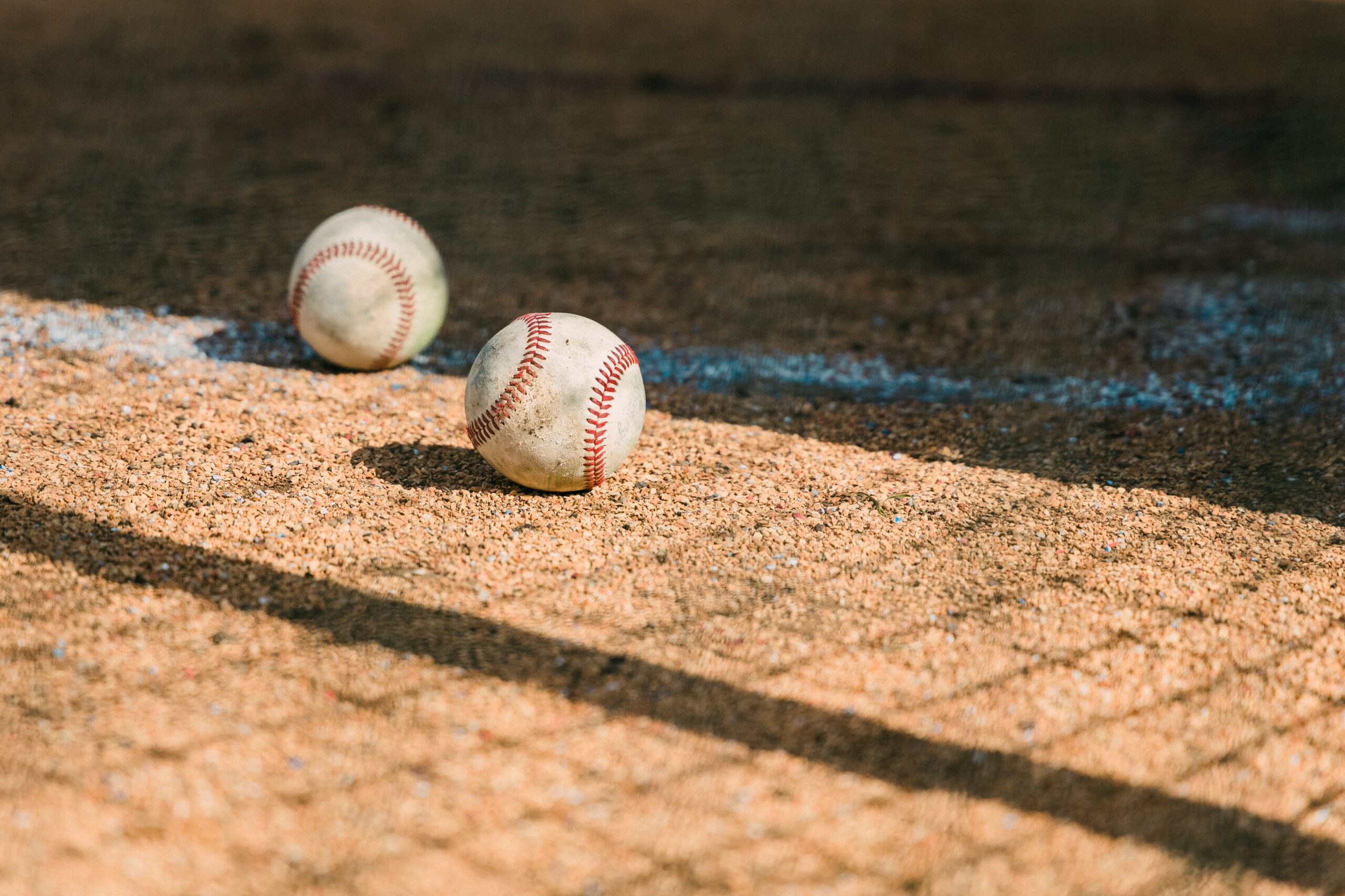 baseballs resting in dirt on baseball field