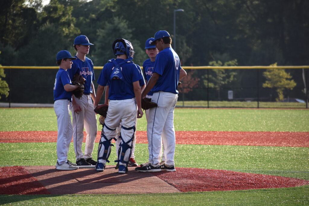 in the dirt team members huddled together at pitchers mound